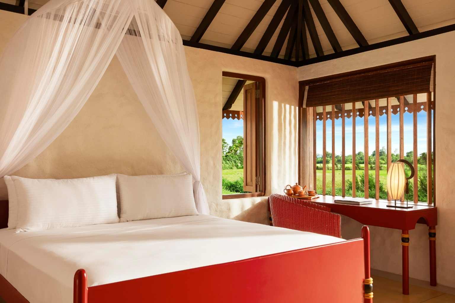 Light-filled bedroom at Jetwing Kaduruketha with four-poster bed and views over rice paddies